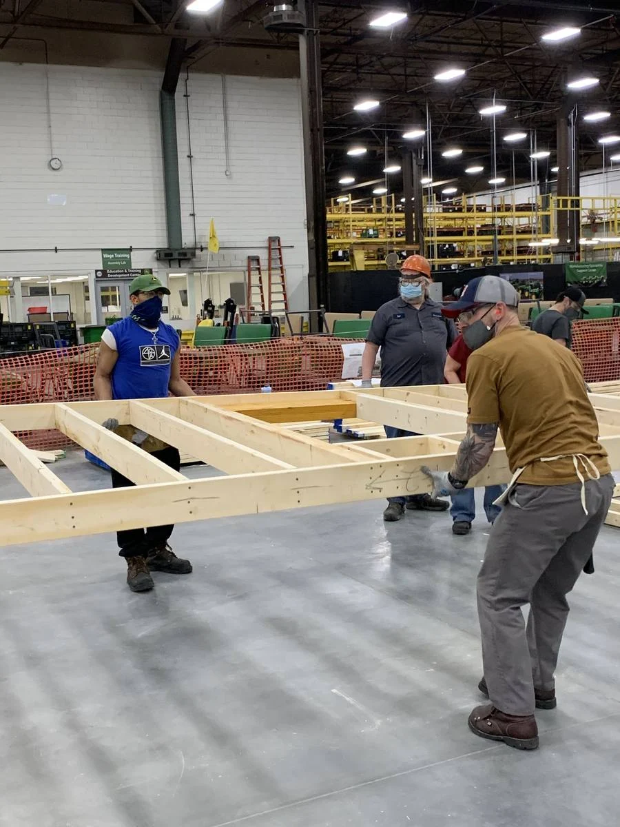 Volunteers constructing home panels inside John Deere plant